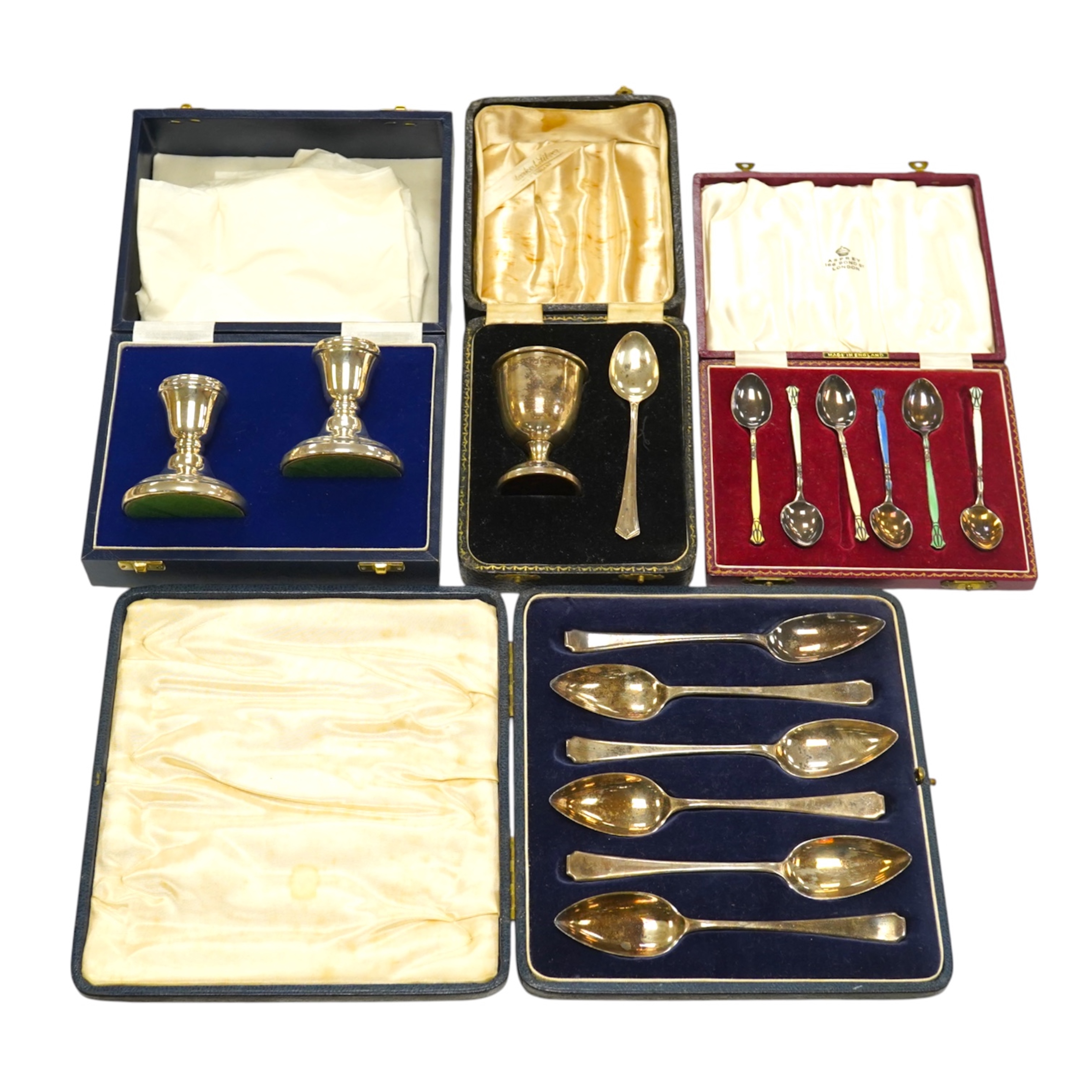 A set of six silver grapefruit spoons, Cooper Brothers & Sons, Sheffield, 1936, a modern pair of silver mounted dwarf candlesticks, a silver egg cup and spoon and a set of six silver gilt and enamelled coffee spoons, all